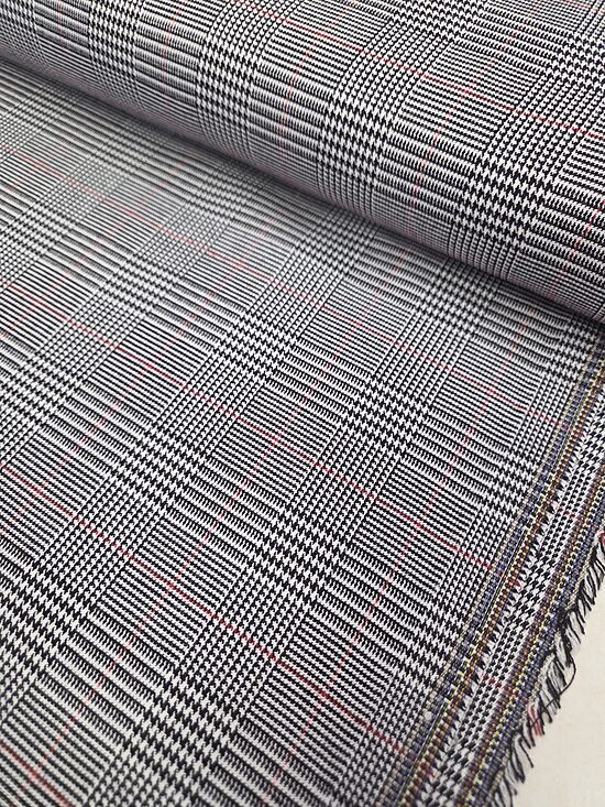 Black-and-white checked suit fabric with a fine houndstooth pattern and a red accent.